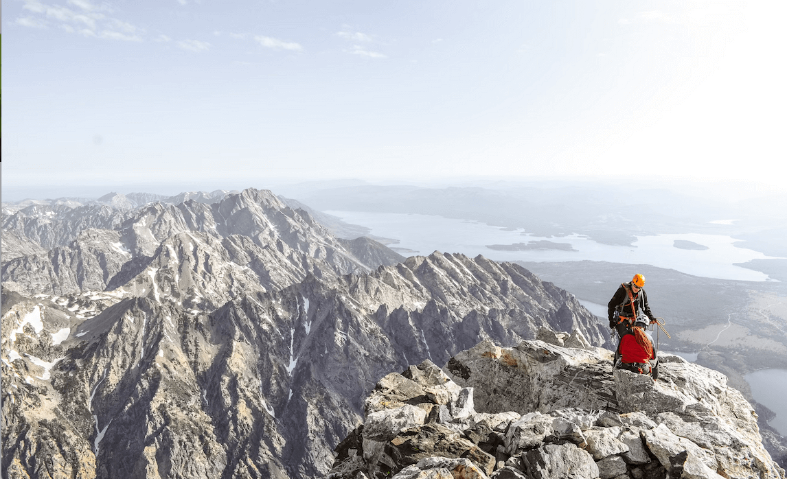 Two climbers reaching the peak, representing perseverance and overcoming challenges.