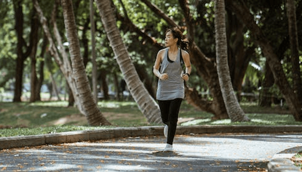 A person jogging in a park surrounded by greenery
